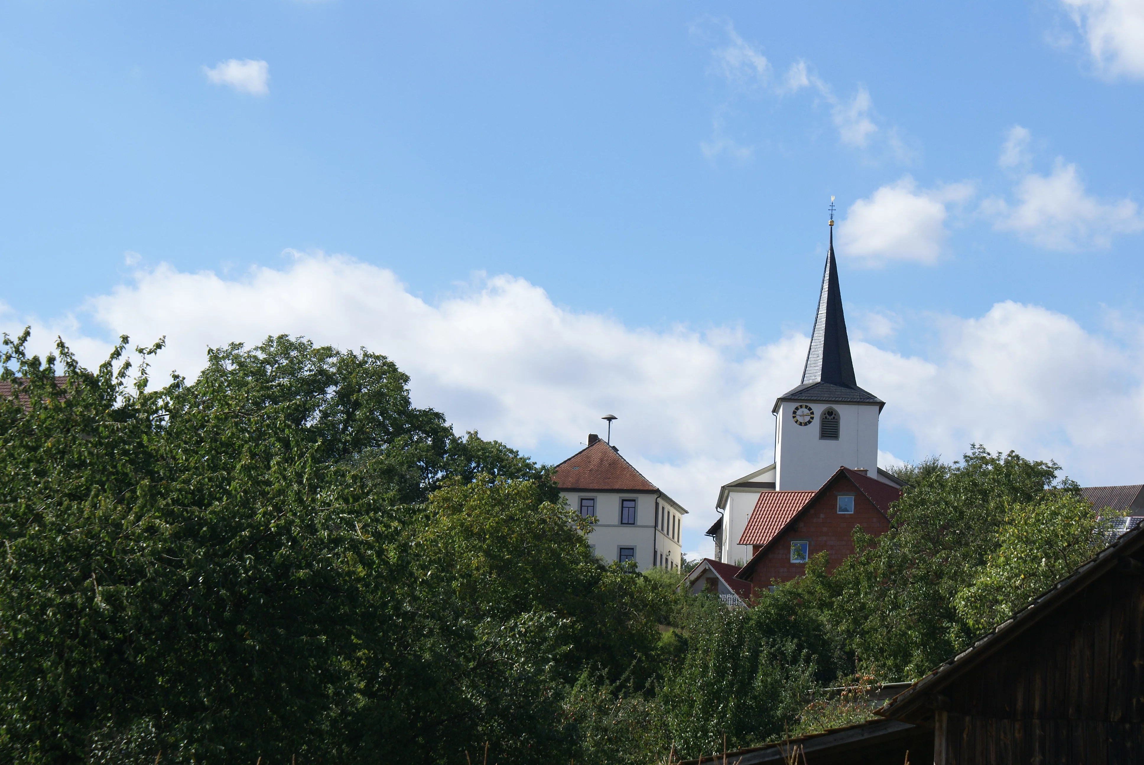Alte Schule und Kirche in Greßhausen Blick auf die Alte Schule und die Kirche in Greßhausen. mit Bäumen im Vordergrund.